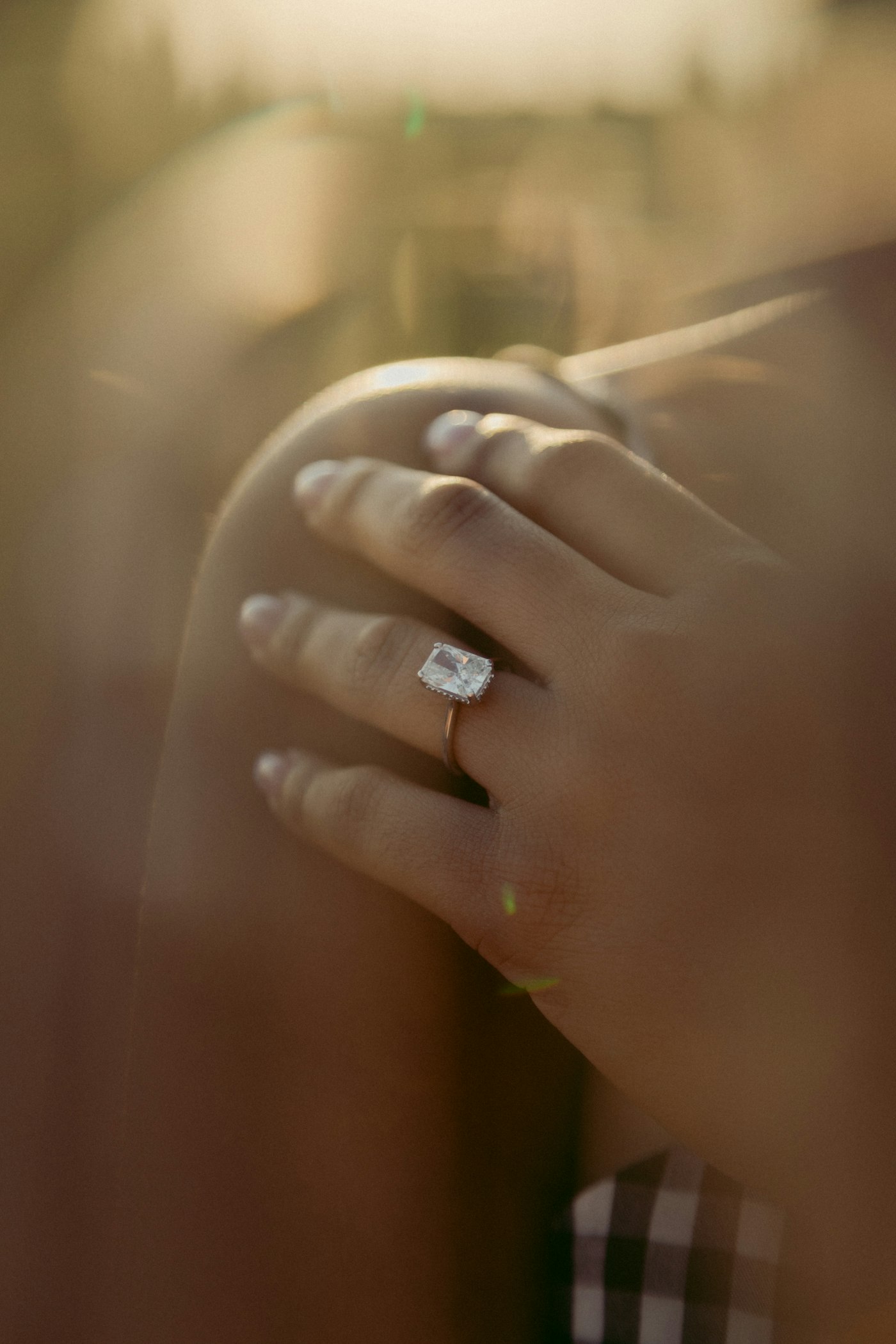Hand wearing a diamond ring in warm light